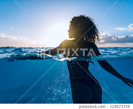 Elegant Woman Swimming Underwater in Clear Tropical Sea 128673359