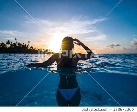 Elegant Woman Swimming Underwater in Clear Tropical Sea 128673360