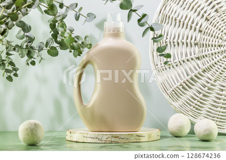 Natural laundry detergent mockup. Washing detergent concept with bottle of washing gel or fabric softener on wooden podium with laundry balls and eucalyptus leaves. Laundry day. Front view Natural laundry detergent mockup. Washing detergent concept with bottle of washing gel or fabric softener on wooden podium with laundry balls and eucalyptus leaves. Laundry day. Front view 128674236