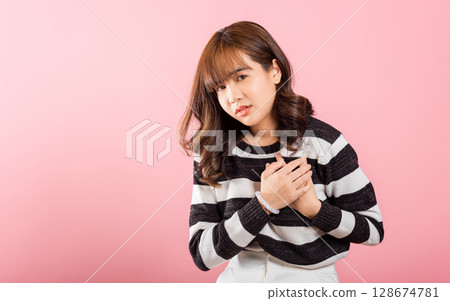 Young woman pressing on chest pain isolated on pink background, painful expression heartache, female having heart attack heart disease, Painful cramps 128674781