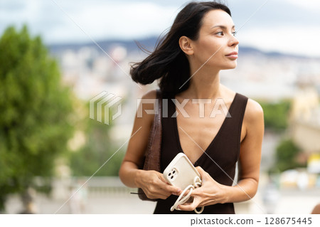 Woman walks through historical center of Barcelona with phone 128675445