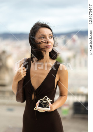 Woman walks through historical center of Barcelona with phone 128675447