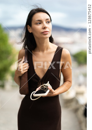 Woman walks through historical center of Barcelona with phone 128675452