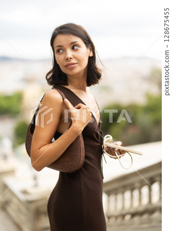 Woman walks through historical center of Barcelona with phone 128675455