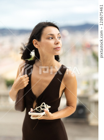 Young woman standing on street with mobile in her hands Young woman standing on street with mobile in her hands 128675461
