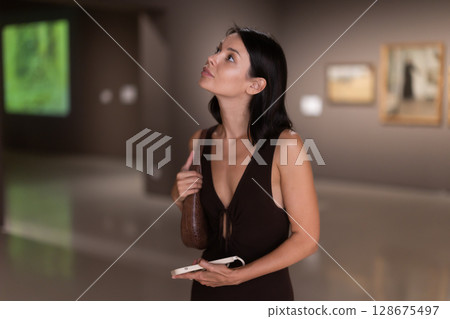 Brunette with phone in hand came to the art gallery 128675497