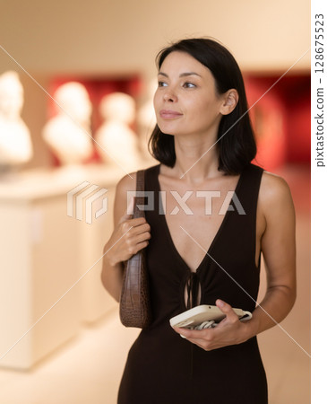 Brunette visits the halls of the museum with interest Brunette visits the halls of the museum with interest 128675523
