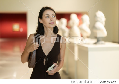 Woman with phone in hands in museum hall, view statues exhibition. 128675526