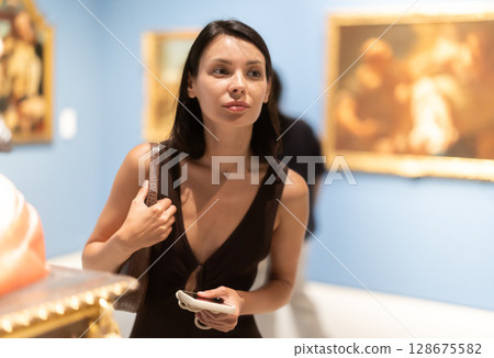 Woman with phone in hands in museum hall, view statues exhibition. 128675582