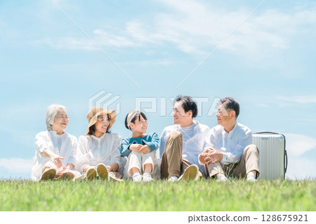 A park with a view of the blue sky, a family sitting on a hill, parents and children, a three-generation family (father, mother, daughter, grandmother, grandfather) A park with a view of the blue sky, a family sitting on a hill, parents and children, a three-generation family (father, mother, daughter, grandmother, grandfather) 128675921