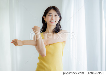 A woman bathing in sunlight through curtains 128676959