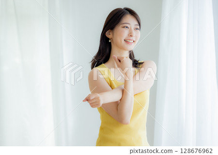 A woman bathing in sunlight through curtains 128676962