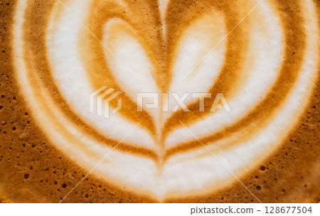 Full frame shot of the surface of hot latte coffee. A latte is a coffee drink made with espresso and steamed milk. 128677504