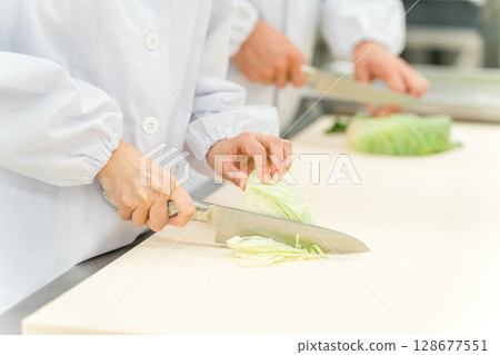 The hands of a staff member cutting cabbage at a food processing plant The hands of a staff member cutting cabbage at a food processing plant 128677551