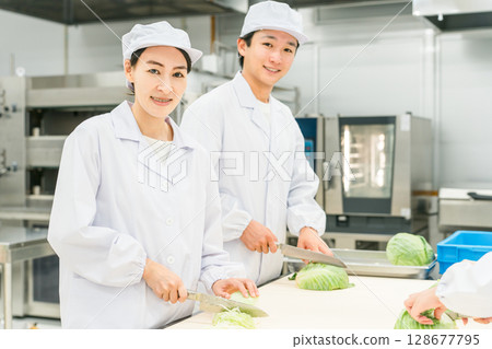 Male and female kitchen staff cutting cabbage in the kitchen 128677795