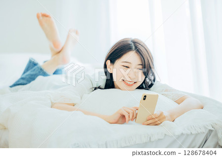 A woman watching a smartphone in bed 128678404