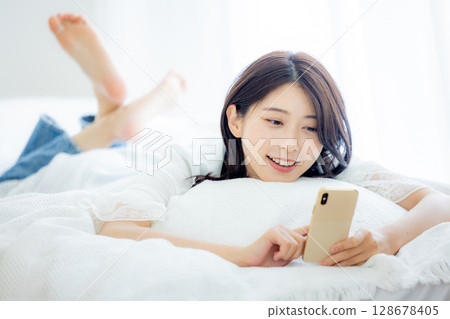 A woman watching a smartphone in bed 128678405