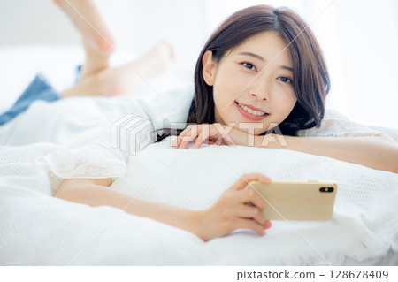 A woman watching a smartphone in bed 128678409