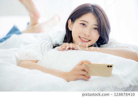 A woman watching a smartphone in bed 128678410