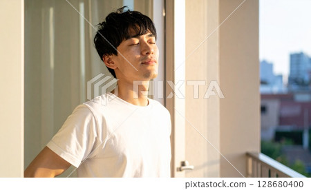 A man in a white T-shirt greets the morning sun 128680400