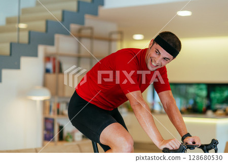 A triathlete riding a triathlon bike on a machine simulation in a modern living room 128680530
