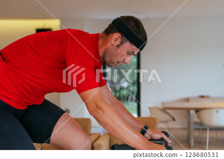 A triathlete riding a triathlon bike on a machine simulation in a modern living room 128680531
