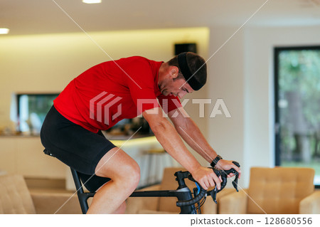 A triathlete riding a triathlon bike on a machine simulation in a modern living room 128680556