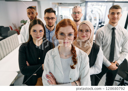 A group of business professionals standing together, taking a well-deserved break from their busy workday, showcasing camaraderie, teamwork, and a moment of relaxation in their dynamic workplace 128680792