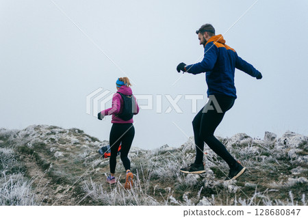 Trail running couple man and woman running on a mountain path 128680847