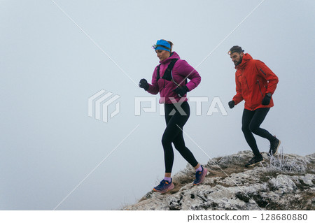 Trail running couple man and woman running on a mountain path 128680880