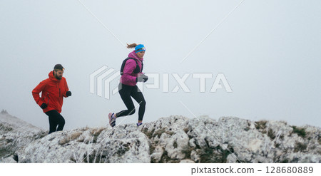 Trail running couple man and woman running on a mountain path 128680889