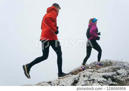 Trail running couple man and woman running on a mountain path Trail running couple man and woman running on a mountain path 128680906