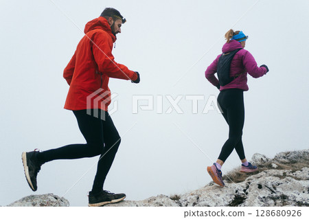 Trail running couple man and woman running on a mountain path Trail running couple man and woman running on a mountain path 128680926