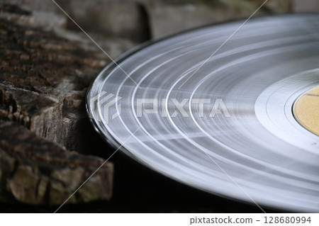 A close-up shot of a vintage vinyl record resting on weathered wood, evoking a nostalgic feel. 128680994