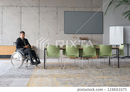A director in a wheelchair sitting alone in an empty office, deeply reflecting on business strategies and decisions, contemplating the path forward with focused determination. 128681075