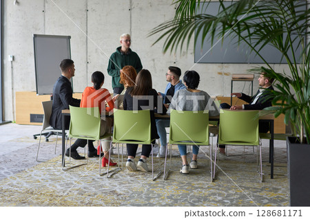 A young, diverse business team sitting together in a modern office, exchanging ideas and business plans, fostering collaboration and innovation for future success. A young, diverse business team sitting together in a modern office, exchanging ideas and business plans, fostering collaboration and innovation for future success. 128681171