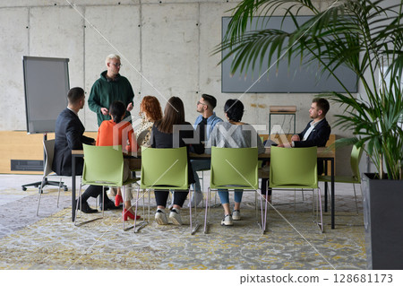 A young, diverse business team sitting together in a modern office, exchanging ideas and business plans, fostering collaboration and innovation for future success. 128681173