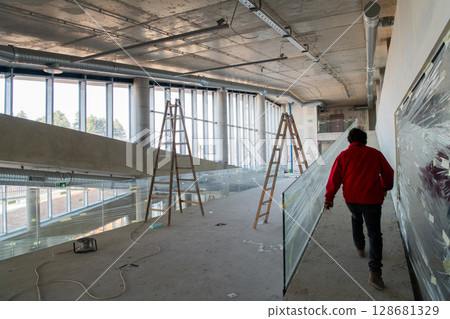 An engineer walks through the construction site, carefully inspecting the ongoing work to ensure quality control and progress in the project An engineer walks through the construction site, carefully inspecting the ongoing work to ensure quality control and progress in the project 128681329