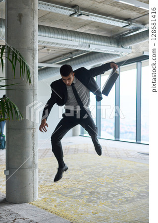 A businessman ecstatically jumping in a modern office, holding a briefcase in his hands, celebrating a moment of success and triumph. A businessman ecstatically jumping in a modern office, holding a briefcase in his hands, celebrating a moment of success and triumph. 128681416