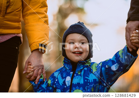 Parents walking hand in hand with their son through the charming city streets, enjoying the warmth of the season and creating joyful memories together 128681429
