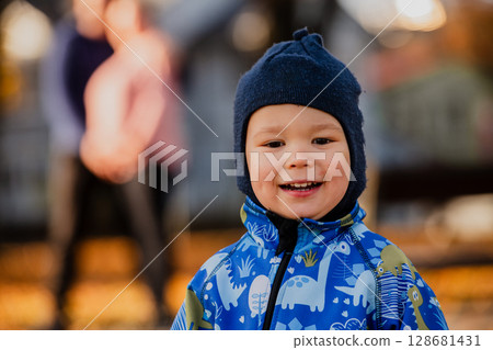 A joyful little boy in his winter coat and hat plays happily in the park, surrounded by the love and warmth of his smiling parents A joyful little boy in his winter coat and hat plays happily in the park, surrounded by the love and warmth of his smiling parents 128681431