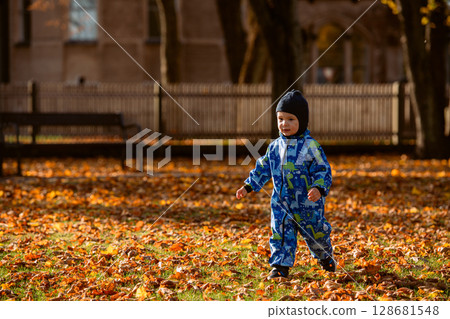 A joyful little boy in his winter coat and hat plays happily in the park, surrounded by the love and warmth of his smiling parents A joyful little boy in his winter coat and hat plays happily in the park, surrounded by the love and warmth of his smiling parents 128681548