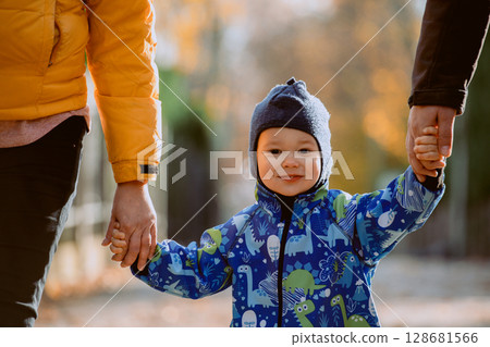 Parents walking hand in hand with their son through the charming city streets, enjoying the warmth of the season and creating joyful memories together Parents walking hand in hand with their son through the charming city streets, enjoying the warmth of the season and creating joyful memories together 128681566