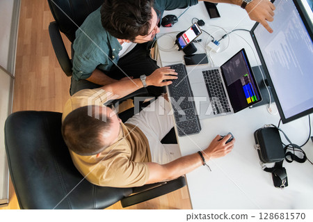 Top view of programmer diligently testing smartphone applications while sitting in their office. 128681570