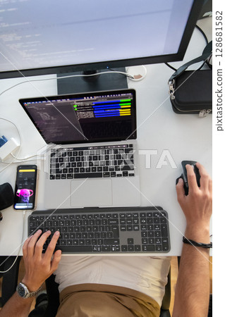 Top view of programmer diligently testing smartphone applications while sitting in their office. Top view of programmer diligently testing smartphone applications while sitting in their office. 128681582
