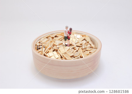 Miniature Couple Standing on Gold Bars in Wooden Bowl 128681586
