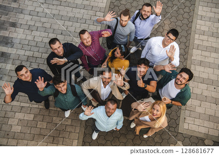 Top view photo of a group of business people and colleagues standing together holding hands, looking towards the camera, symbolizing unity and teamwork. Top view photo of a group of business people and colleagues standing together holding hands, looking towards the camera, symbolizing unity and teamwork. 128681677