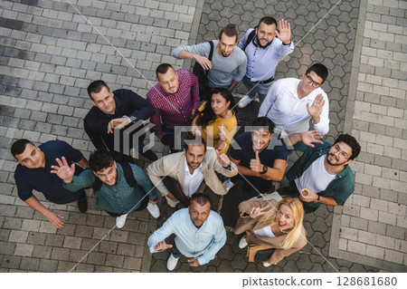 Top view photo of a group of business people and colleagues standing together holding hands, looking towards the camera, symbolizing unity and teamwork. 128681680