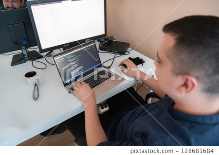 A programmer diligently testing smartphone applications while sitting in their office. 128681684