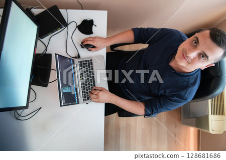 Top view of programmer diligently testing smartphone applications while sitting in their office. Top view of programmer diligently testing smartphone applications while sitting in their office. 128681686
